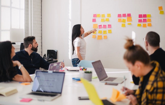 Five people in a meeting with sticky notes Five people in a meeting with sticky notes